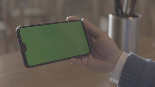 男性拿着绿色屏幕的手机