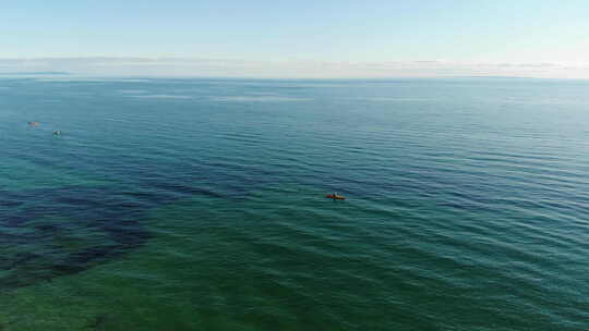 在平静的蓝色大海中，围绕一名皮划艇运动员