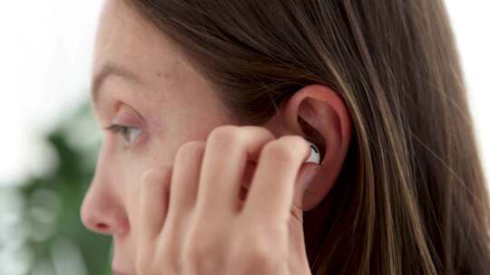 女孩将无线白色耳机插入耳朵