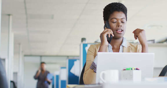 非裔美国女商人在办公室使用笔记本电脑和智能手机，慢动作
