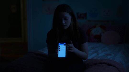 女孩夜晚在床上使用智能手机