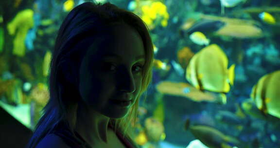 一个迷人的年轻女人凝视着天网宫里的鱼