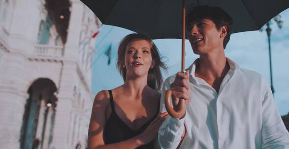 情侣打着遮阳伞在街头散步