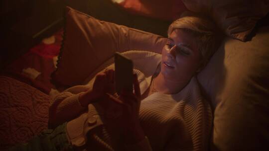 夜晚女人躺在床上玩手机