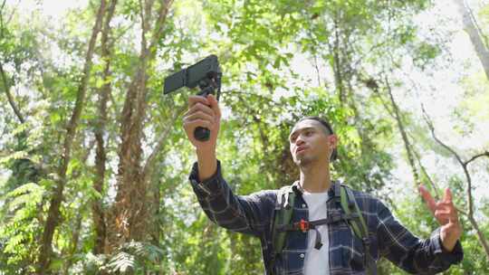 亚洲帅气男背包客vlogger独自在森林里旅行。视频素材模板下载