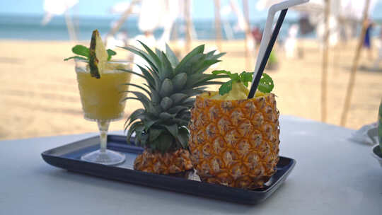海边沙滩背景的新鲜菠萝汁