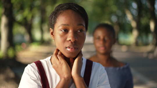 陷入困境的苗条年轻非裔美国妇女站在公园里