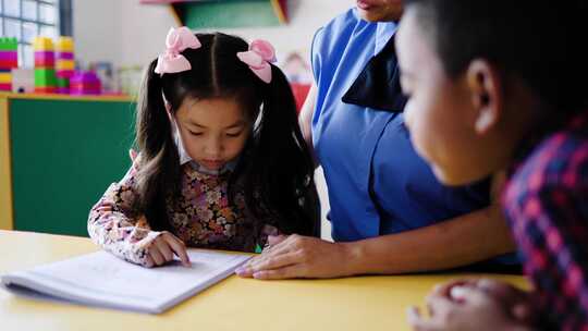 老师在幼儿园教室帮助学生学习阅读。多种族