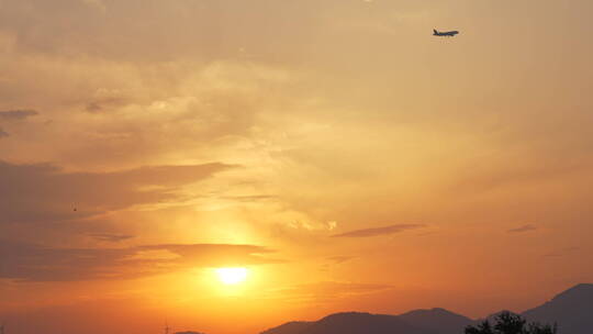 夕阳日落余晖的天空下飞机飞过电塔信号塔