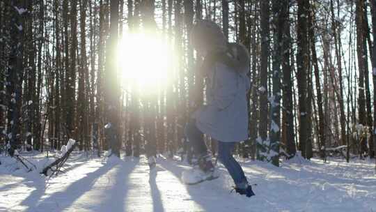 冬天阳光透过树林时，女孩踢起雪