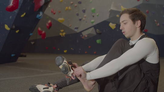 男运动员坐在抱石体育馆里穿登山鞋视频素材模板下载