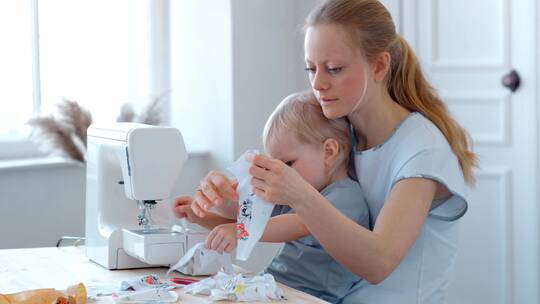 母亲抱着婴儿在缝纫机前做手工