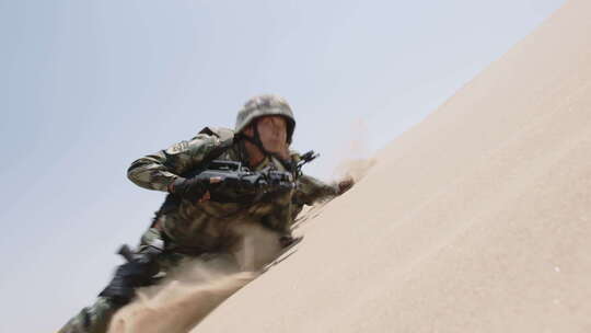 边防战士背枪趴在沙地中匍匐前进