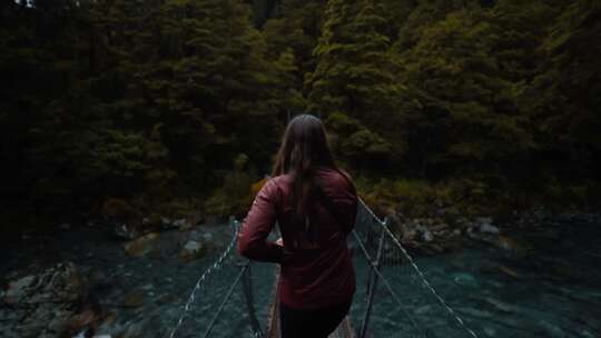 女人在森林河上穿过一座狭窄的木桥