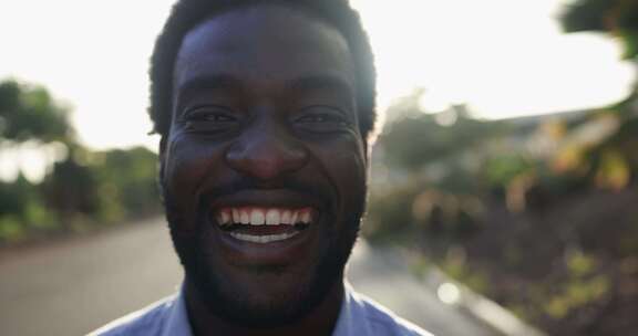 背景是日落的城市里，年轻的非洲男子在镜头前微笑