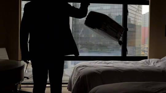 男子进入房间扔下行李箱站在窗前视频素材模板下载