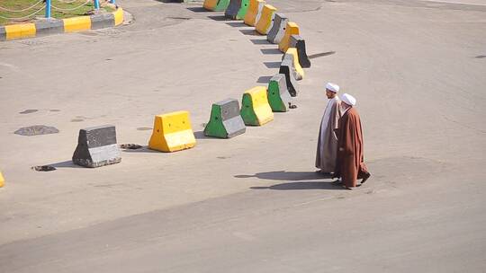 两个穿阿拉伯长袍的男人穿过街道
