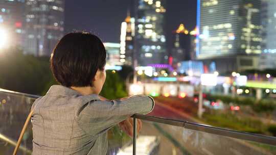 夜晚年轻女性看着城市背影