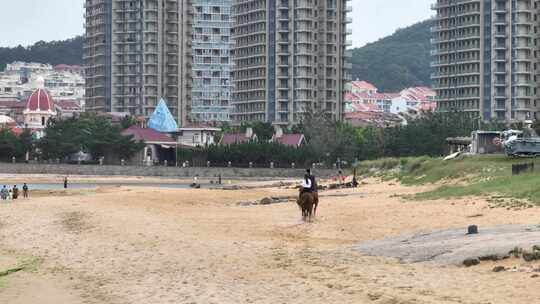 航拍威海市环翠区金海路沙滩上的骑马人