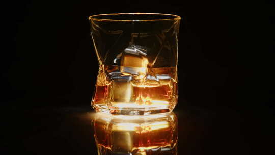 玻璃威士忌，黑色背景上有冰冷的石头，在镜