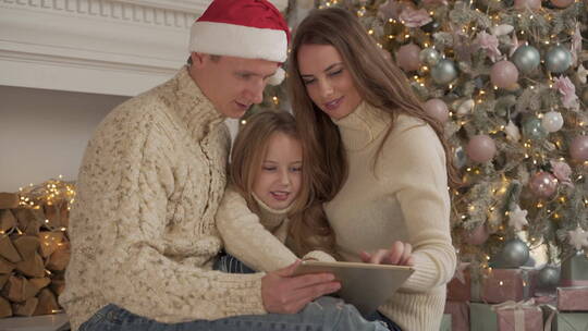圣诞节父母和女儿一起看平板