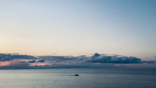 海上日出时孤船行驶的唯美画面