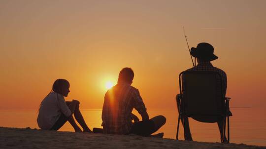 夕阳下父子在海滩钓鱼剪影