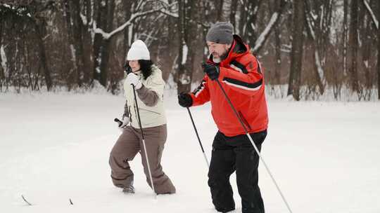 一男一女拿着登山杖在雪地里行走