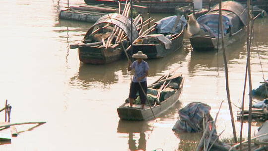 波光粼粼夕阳下渔民撑船于渔船间