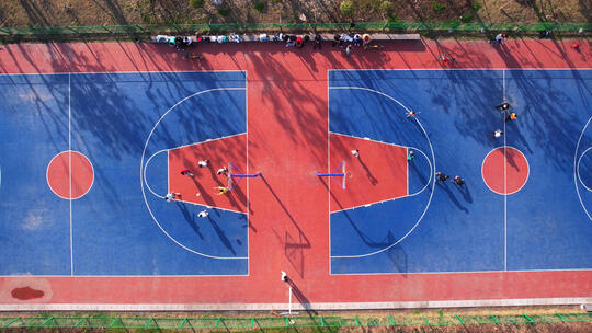 航拍城市校园篮球场上运动健身比赛的少年