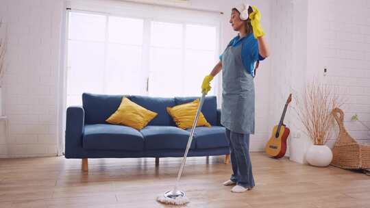 亚洲年轻女子清洁工在打扫客厅时跳舞。视频素材模板下载