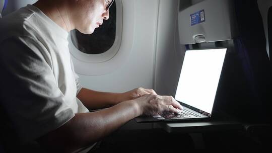 男子在飞机上使用笔记本电脑