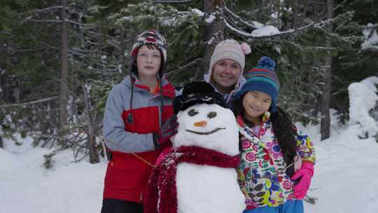 孩子们和他们的母亲在他们堆的雪人旁边拍照