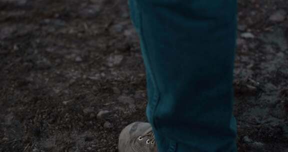 穿着牛仔裤和工作鞋走在泥土上的男人