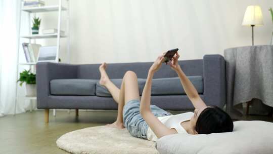 女子躺地玩手机居家场景