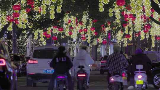 挂满彩灯的街道夜景：电瓶车与汽车，行人