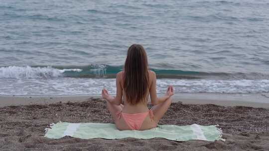 女生在海边打坐疗养静心坐瑜伽冥想