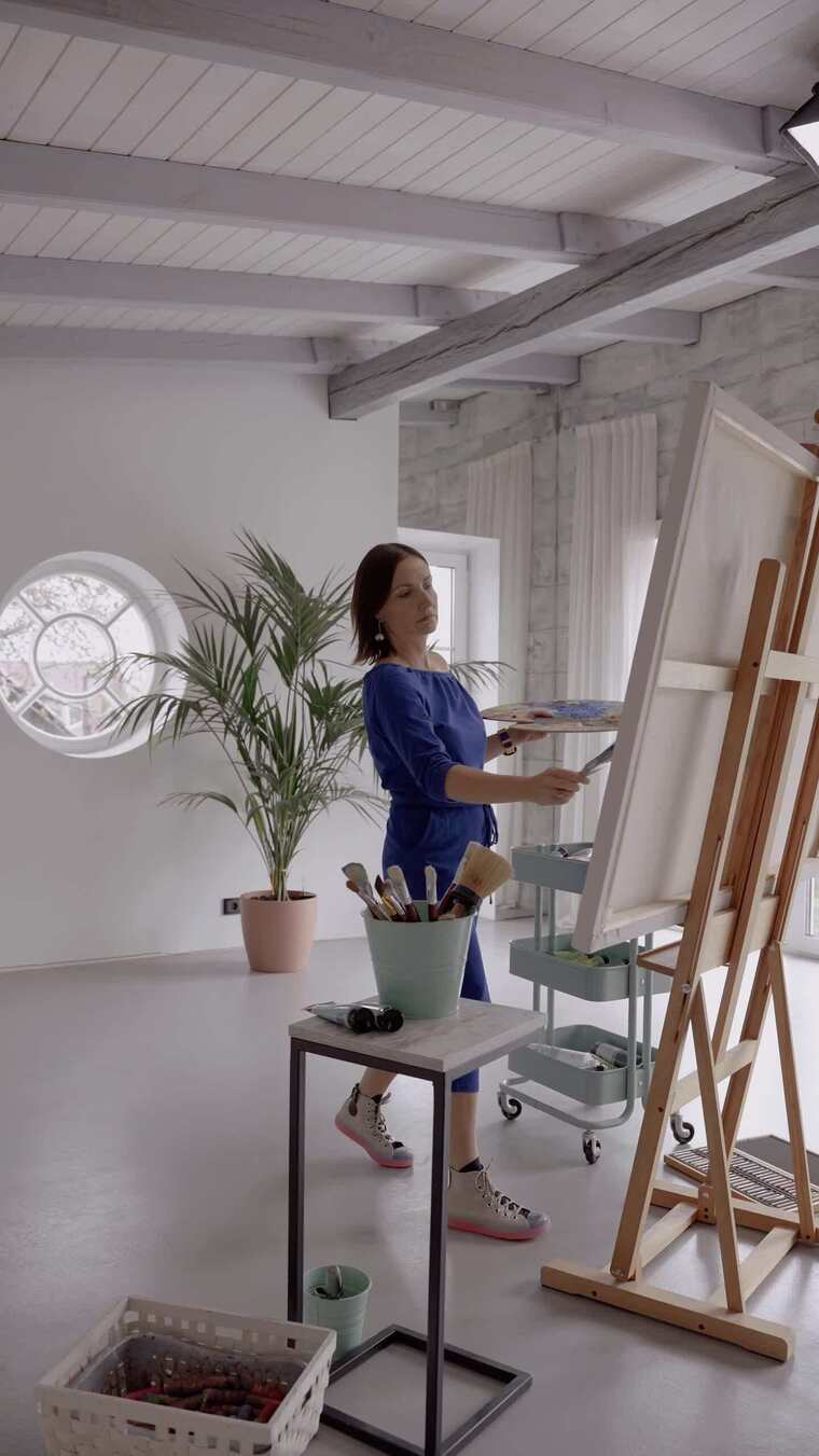 一个拿着调色板在画布上画画的女人