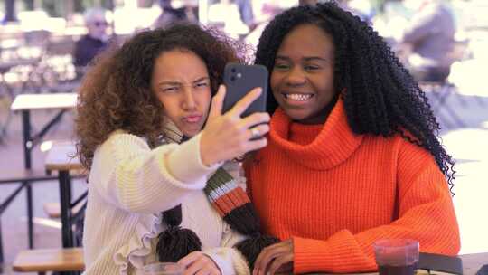 无忧无虑的年轻黑人女孩和西班牙裔女孩自拍做鬼脸