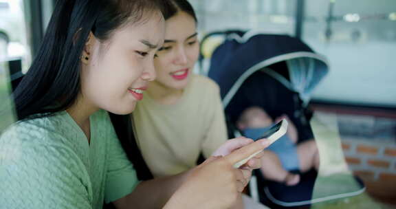 两个亚洲女人正在手机屏幕上看东西。