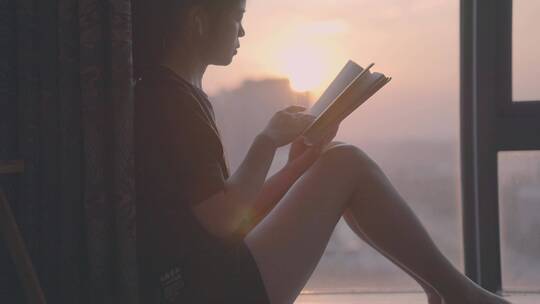 女孩坐在落地窗前看书，唯美窗边夕阳