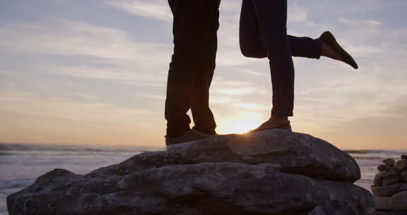 一对夫妇站在海边的岩石上