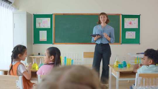 可爱的学生在小学教室里和老师一起学习。