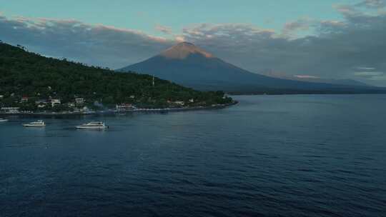 日出时巴厘岛阿贡火山和大海的阿梅德村鸟瞰