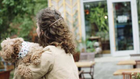 女子抱着泰迪犬小狗站在户外街上行走