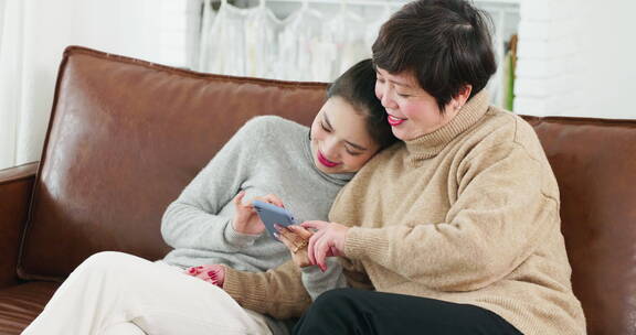 美女和妈妈在沙发上看手机一起网购