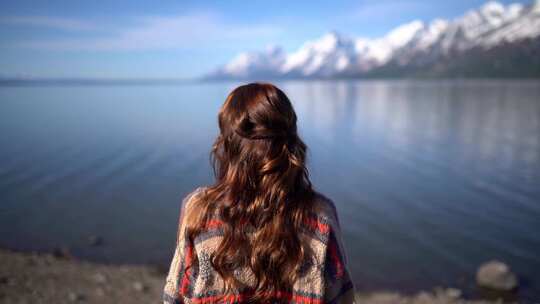 女孩孤独坐在雪山的湖泊前视频素材模板下载
