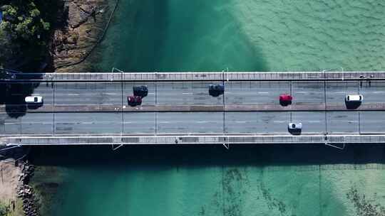汽车和行人在横跨风景优美的海洋河口的桥上行驶。平移