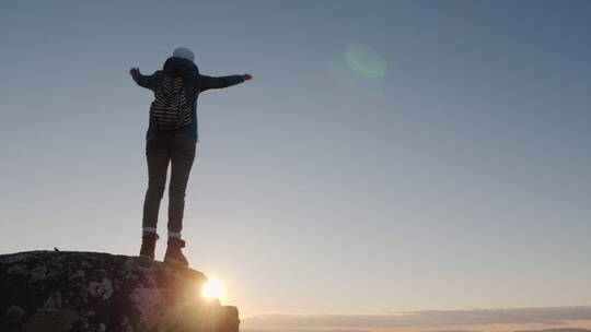 一位成功的女旅行者在山顶举起双手庆祝到达山顶