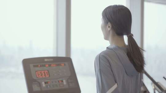 亚洲东方中国女性跑步机跑步时戴蓝牙耳机